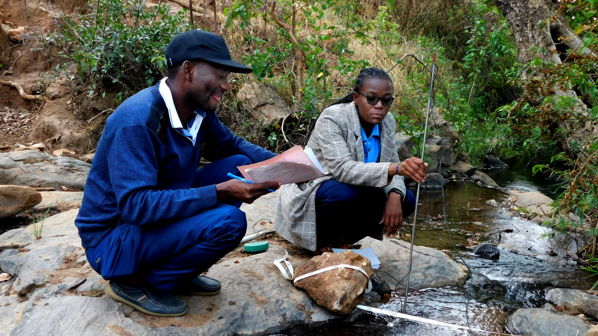 A woman and man measure water quality of a stream