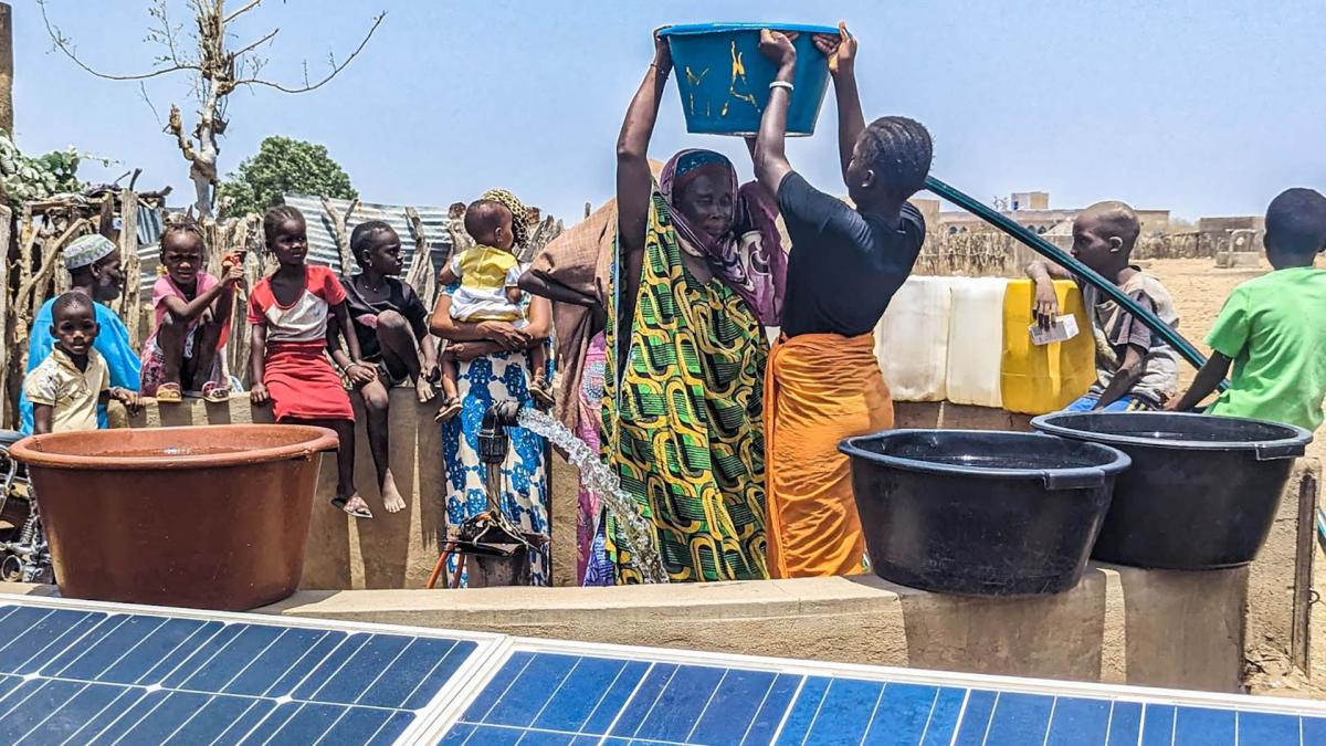 A woman fills barrels with water from a solar powered water pump.