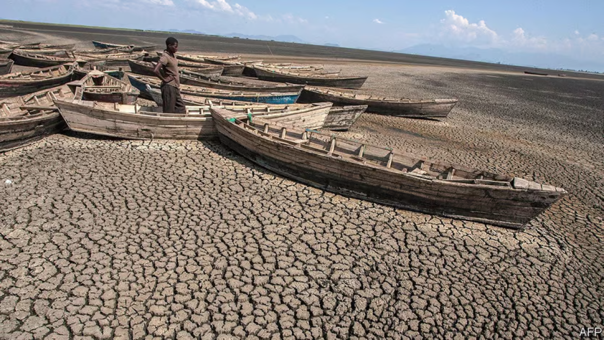 a person stands with small, empty boats in a dry lakebed