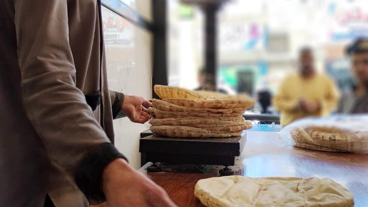 A bakery employee weighs flatbreads to fulfill a customer's order.