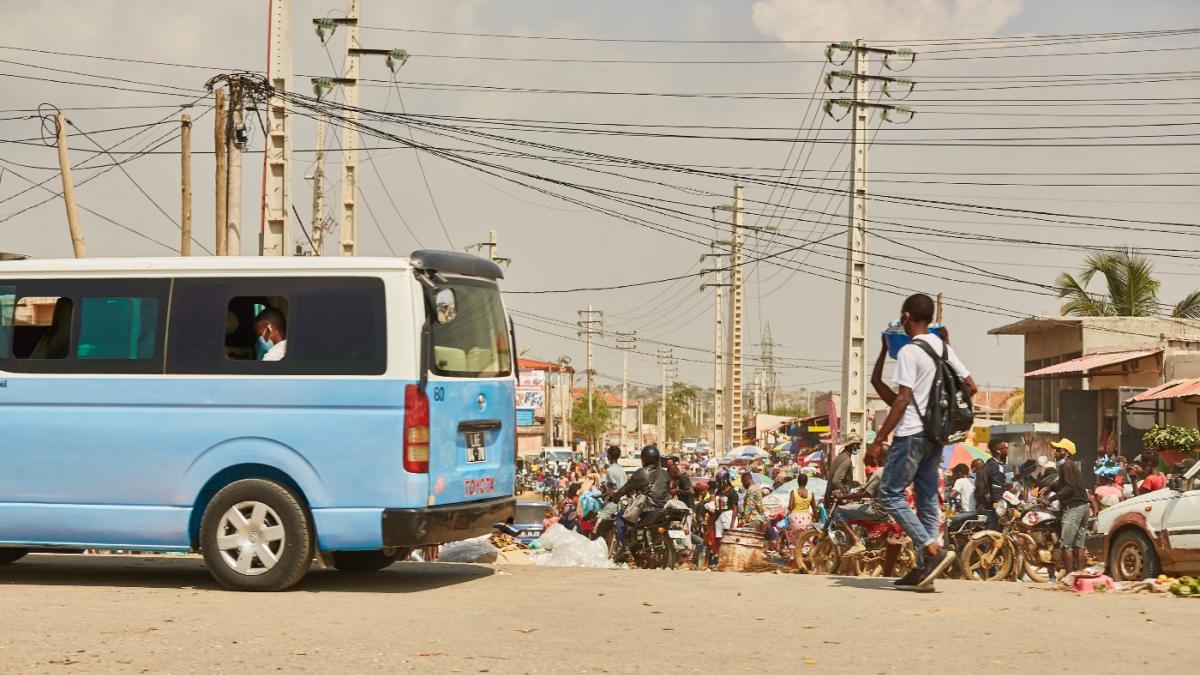 A blue taxi, a man walking and crisscrossing power lines in Luanda.