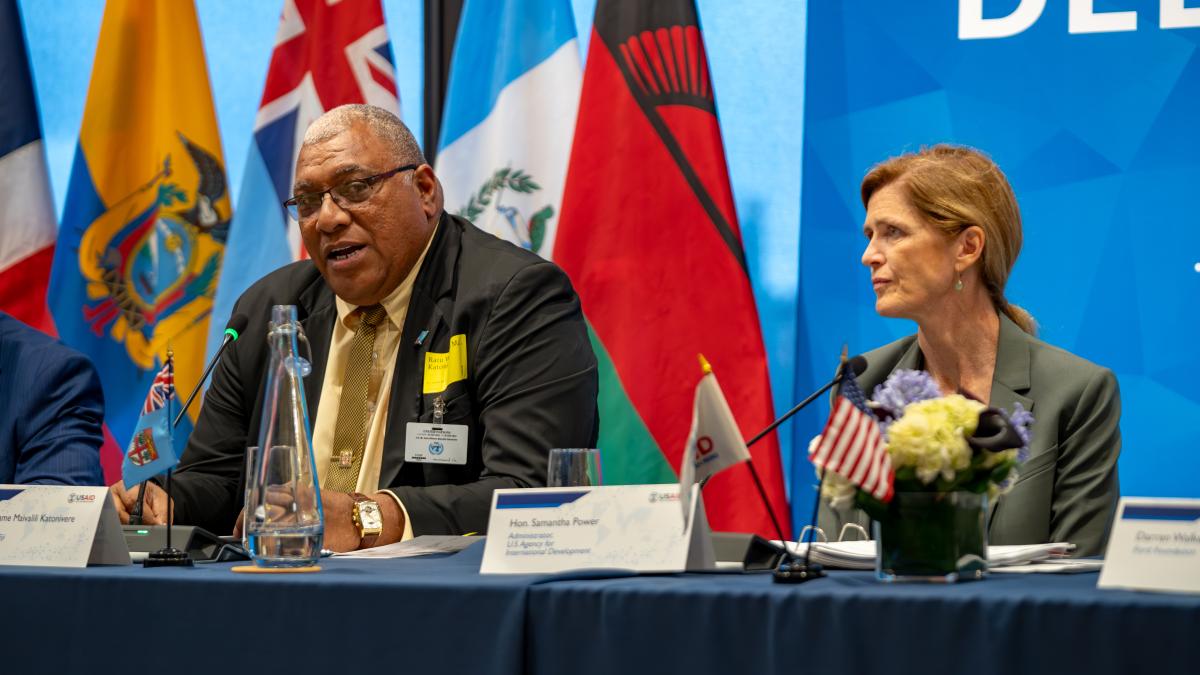 Fijian President Ratu Wiliame Katonivere, wearing a dark suit and gold tie delivering remarks at the “Democracy Delivers” event co-hosted by USAID and the Ford Foundation during the UN General Assembly in New York. USAID Administrator Samantha Power, dressed in a light gray suit, is seated next to him.