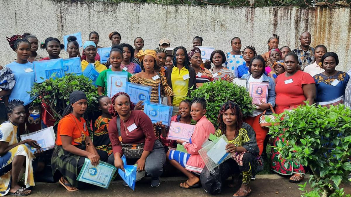 A group of three dozen people pose for a photo with certificates in a garden