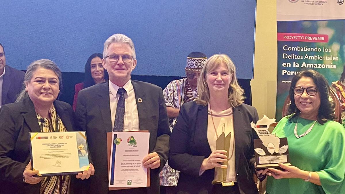 Four people standing next to each other and smiling while holding awards received by the Prevent project