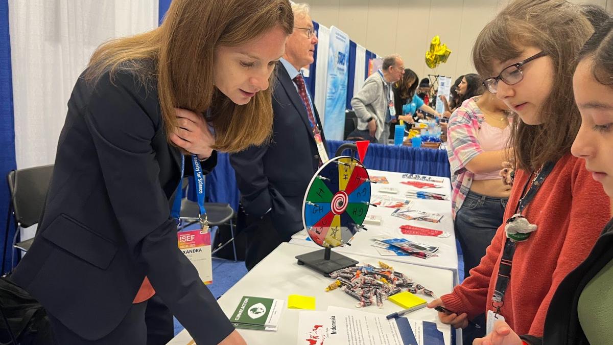 An adult and children look at a science project display