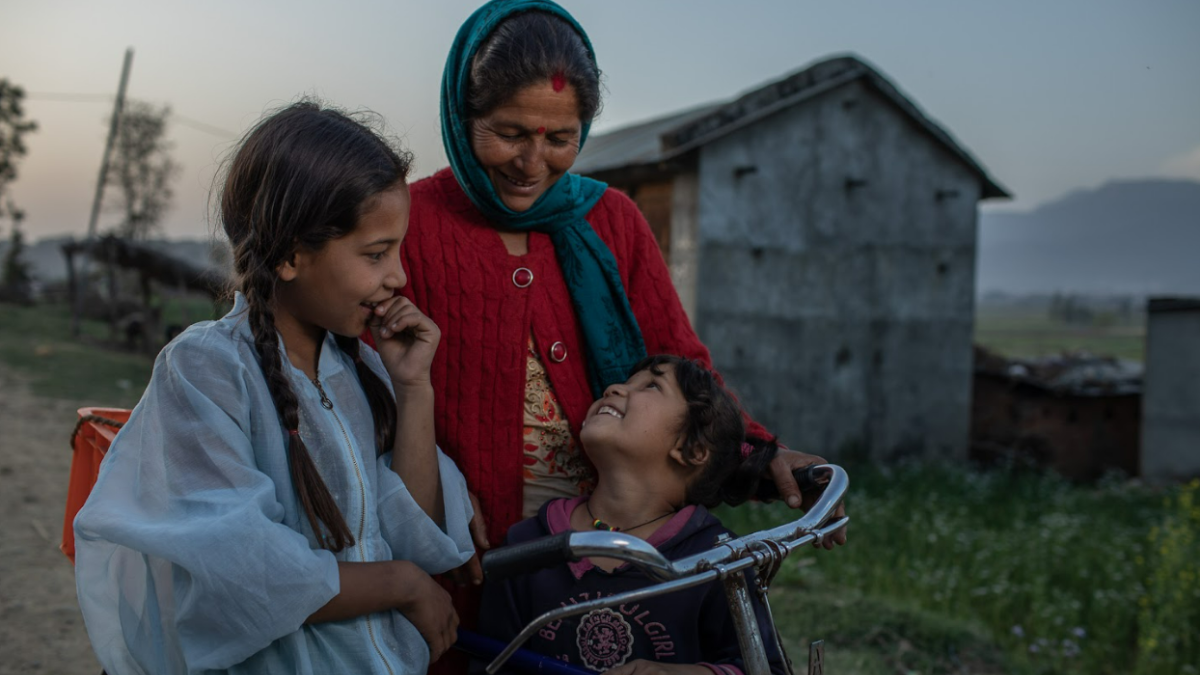 A woman and her two young daughters look at each other while sitting on a bike.