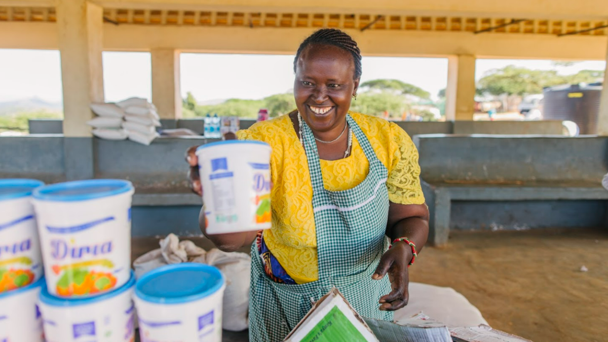 A smiling woman in Kenya stacks tubs labeled Diria.