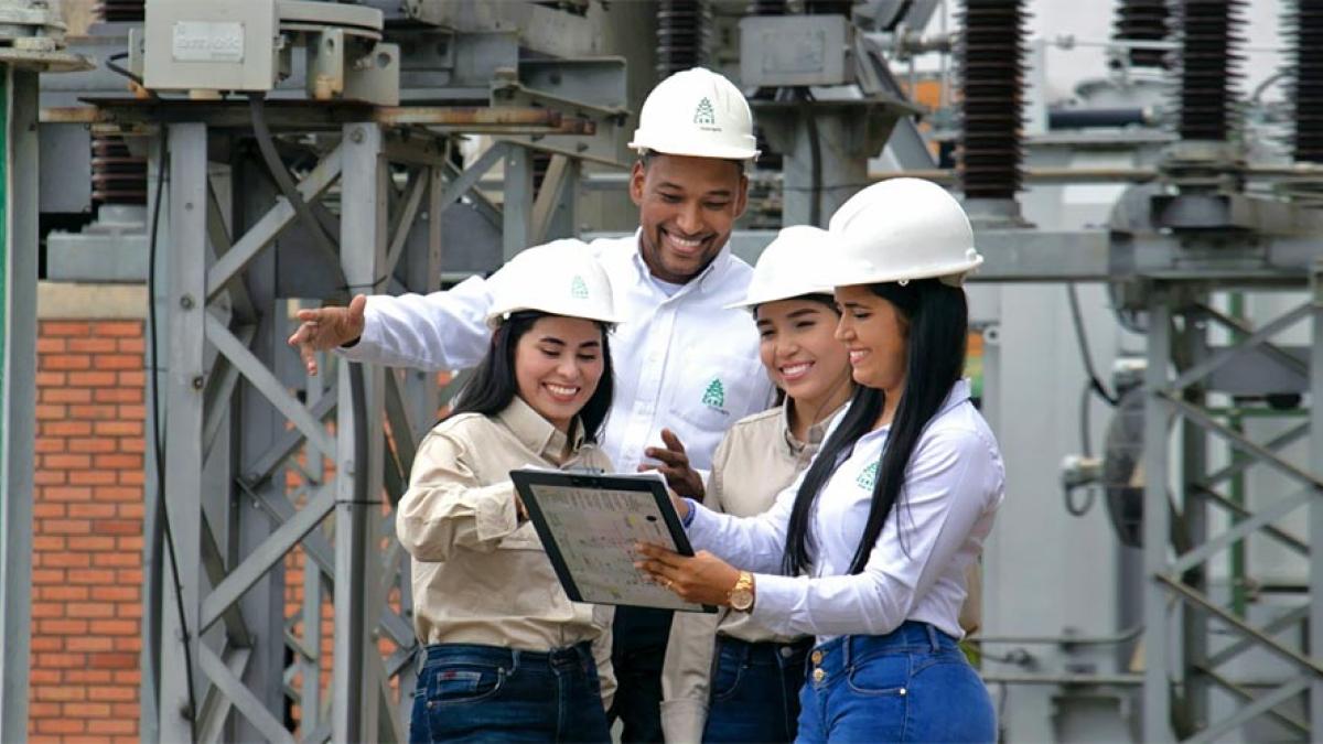 A small group of happy female and male engineers in hard hats review technical documents at a power station 