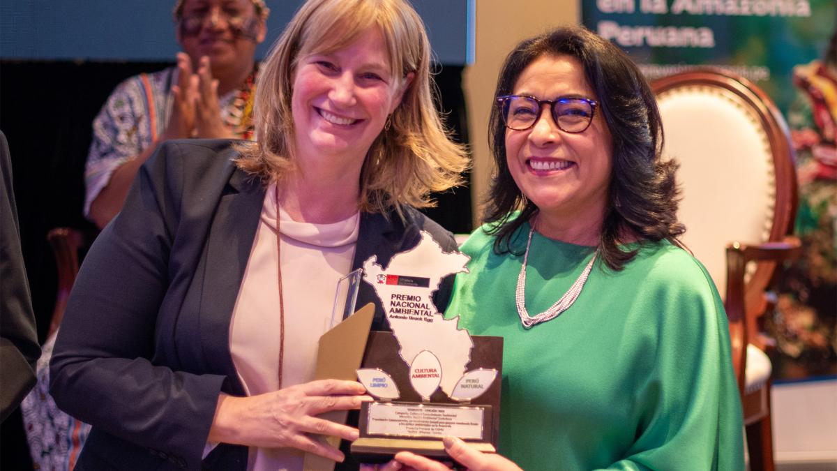 USAID Peru Mission Director and Prevent project director smiling holding the environmental citizenship trophy