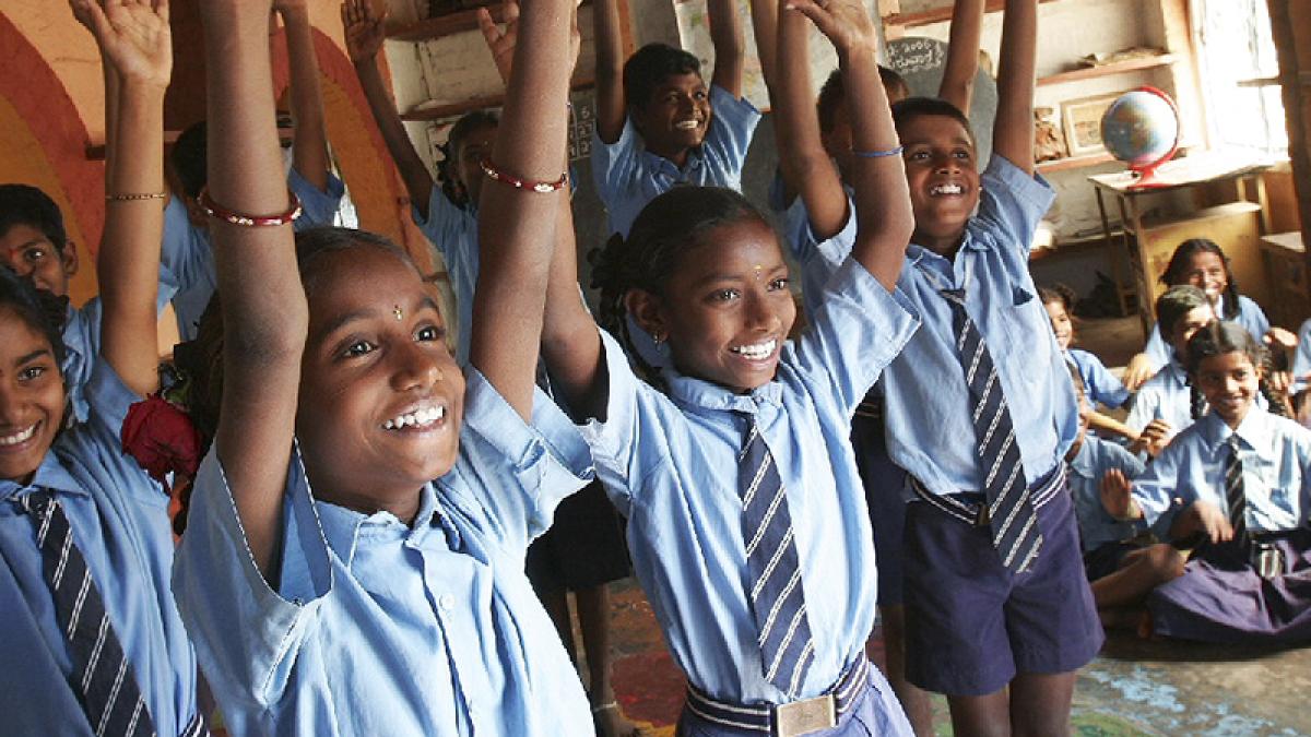 School children smiling with hands raised