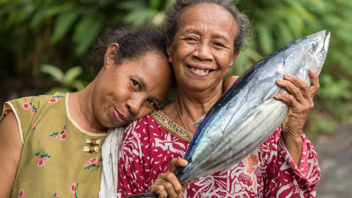 Cheerful women proudly display a fresh skipjack tuna in Banda Neira, Maluku islands.