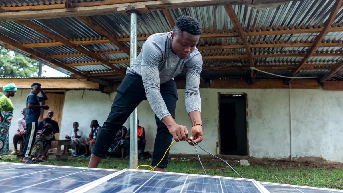 A man working on cables of a solar panel lying on the ground