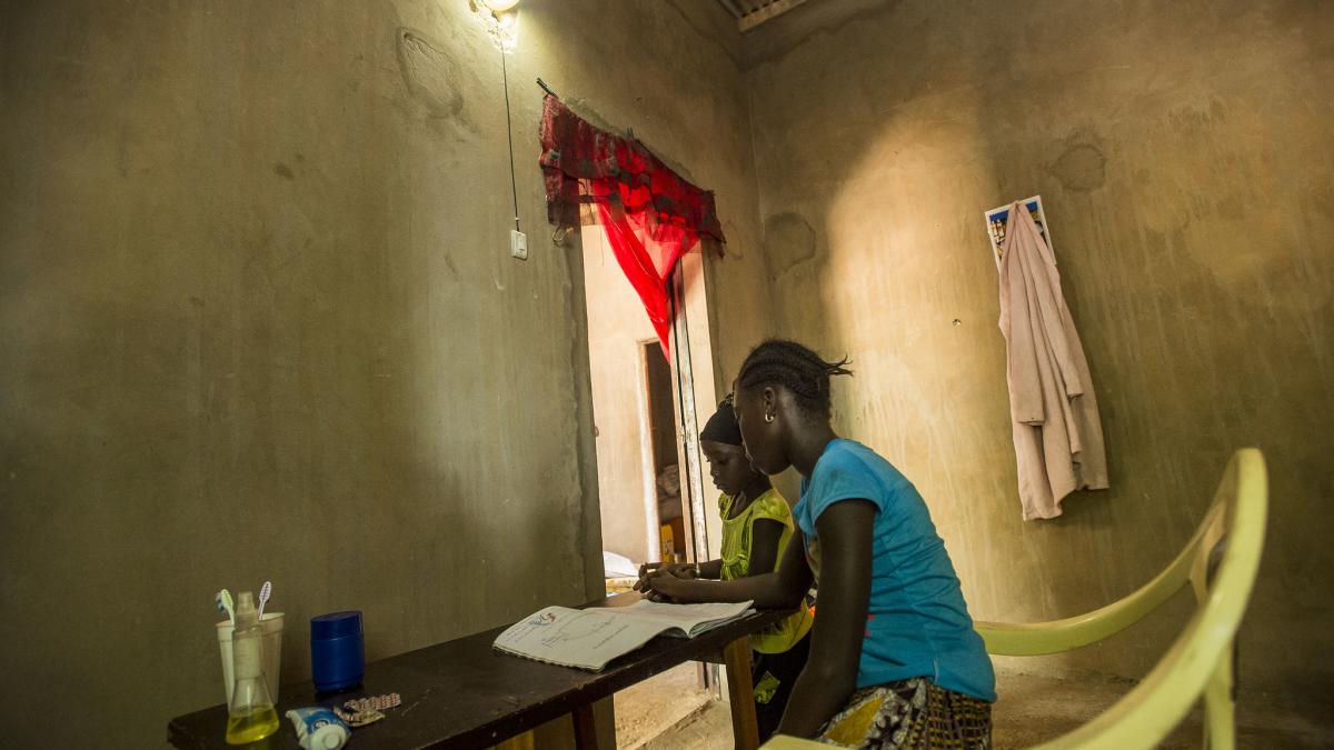 Two children studying at a desk under a light