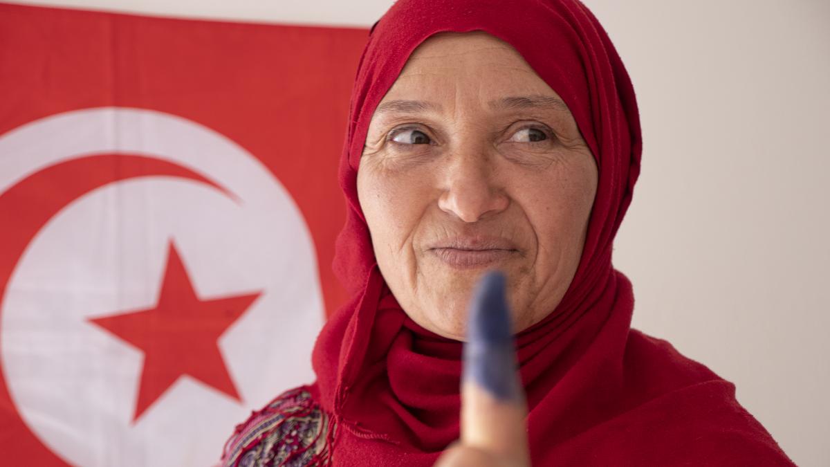 A Tunisian woman holds up an ink-dyed finger to signify she has cast a vote