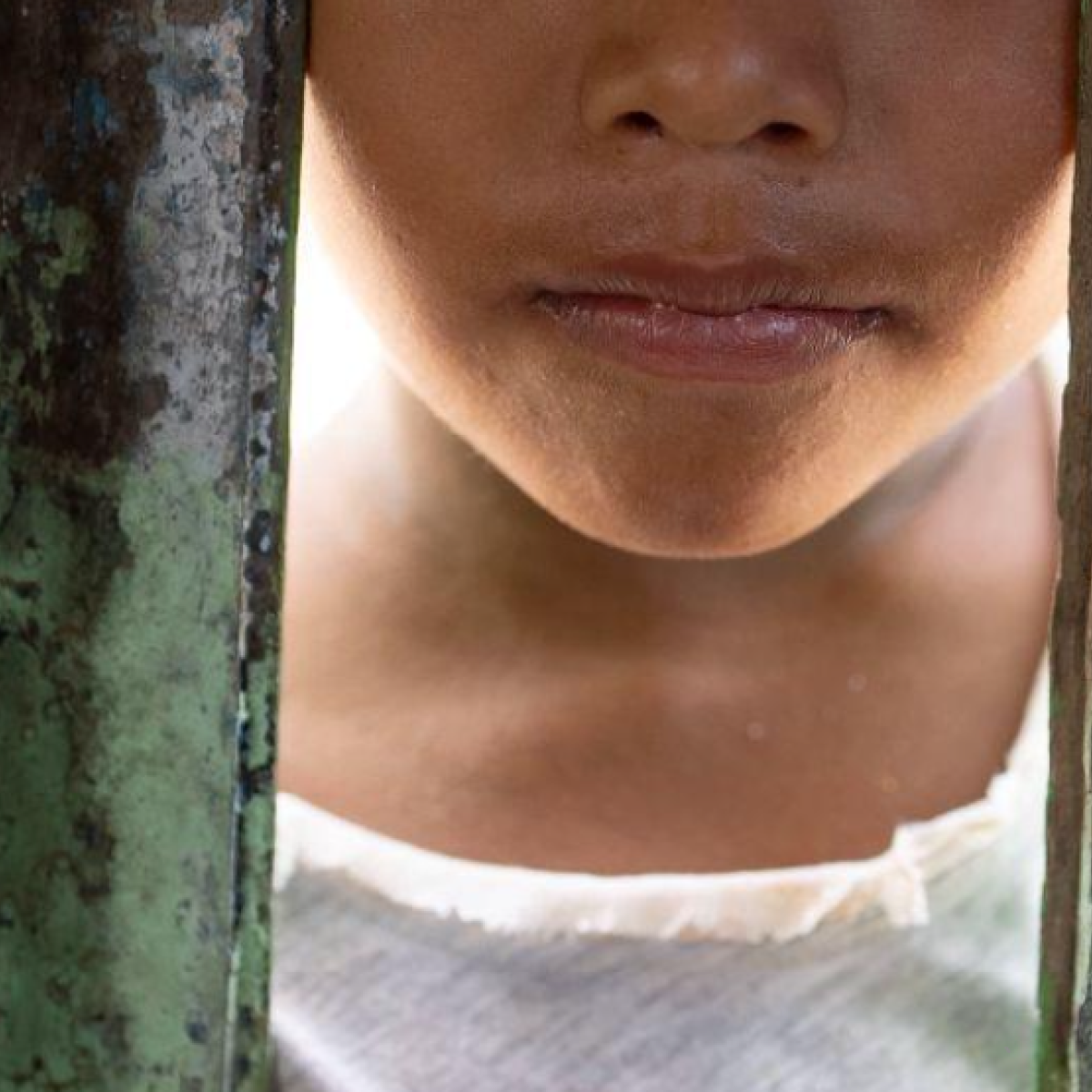 A child looking through a wooden wall