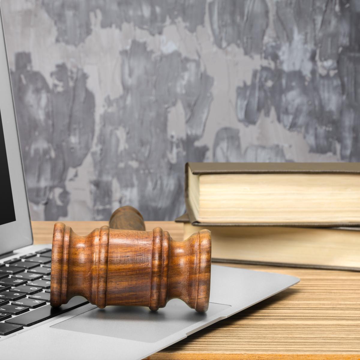 A gavel on a laptop and some papers on a desk