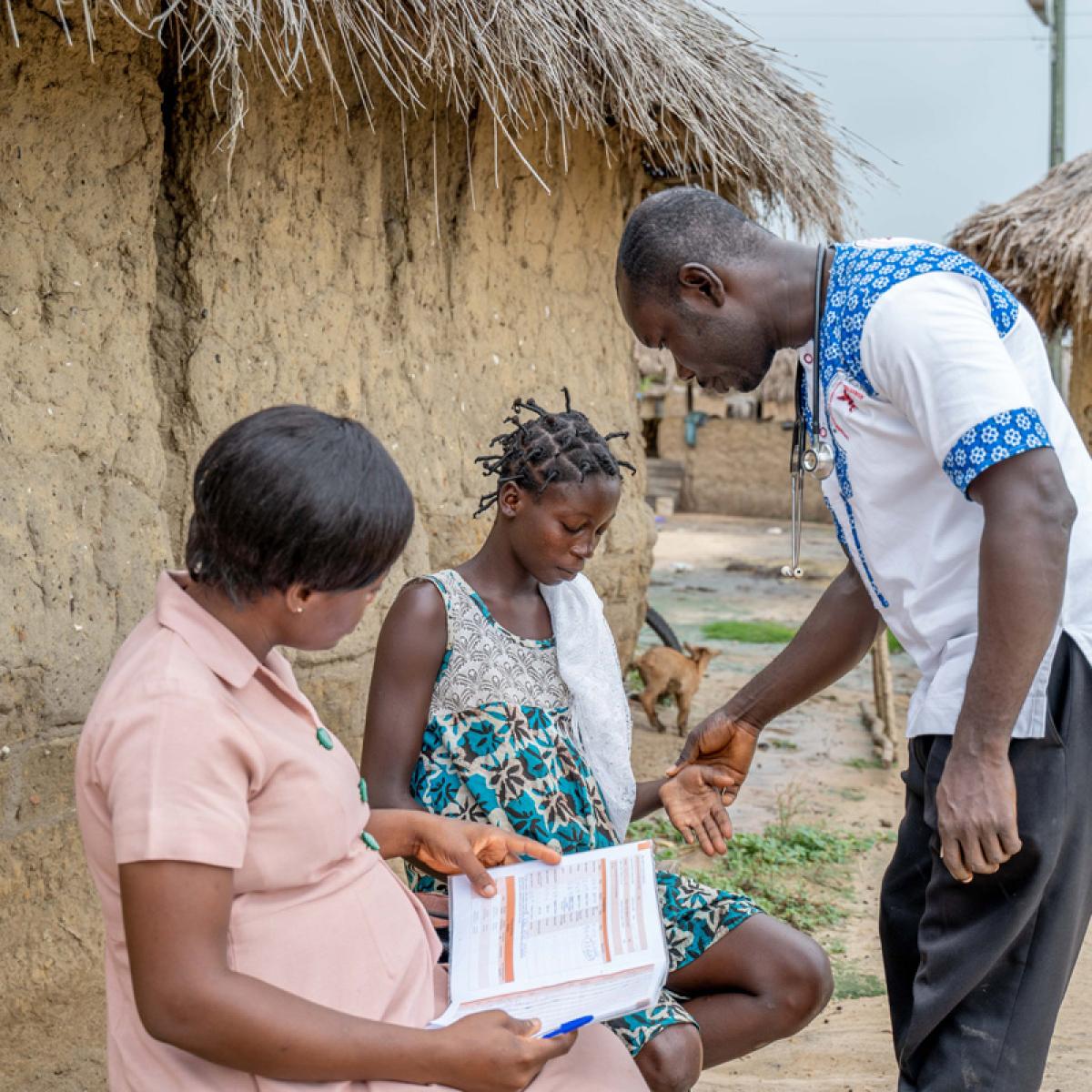 A Physician Assistant/Network Leader supports a community health officer following up with a referred client at home.