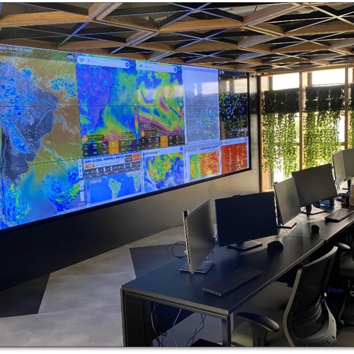 A room with a large screen with data and maps