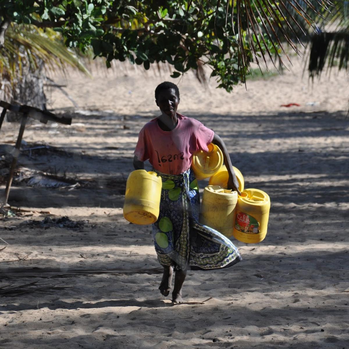 Rehema Ngowa collects water from the newly rehabilitated well in her community