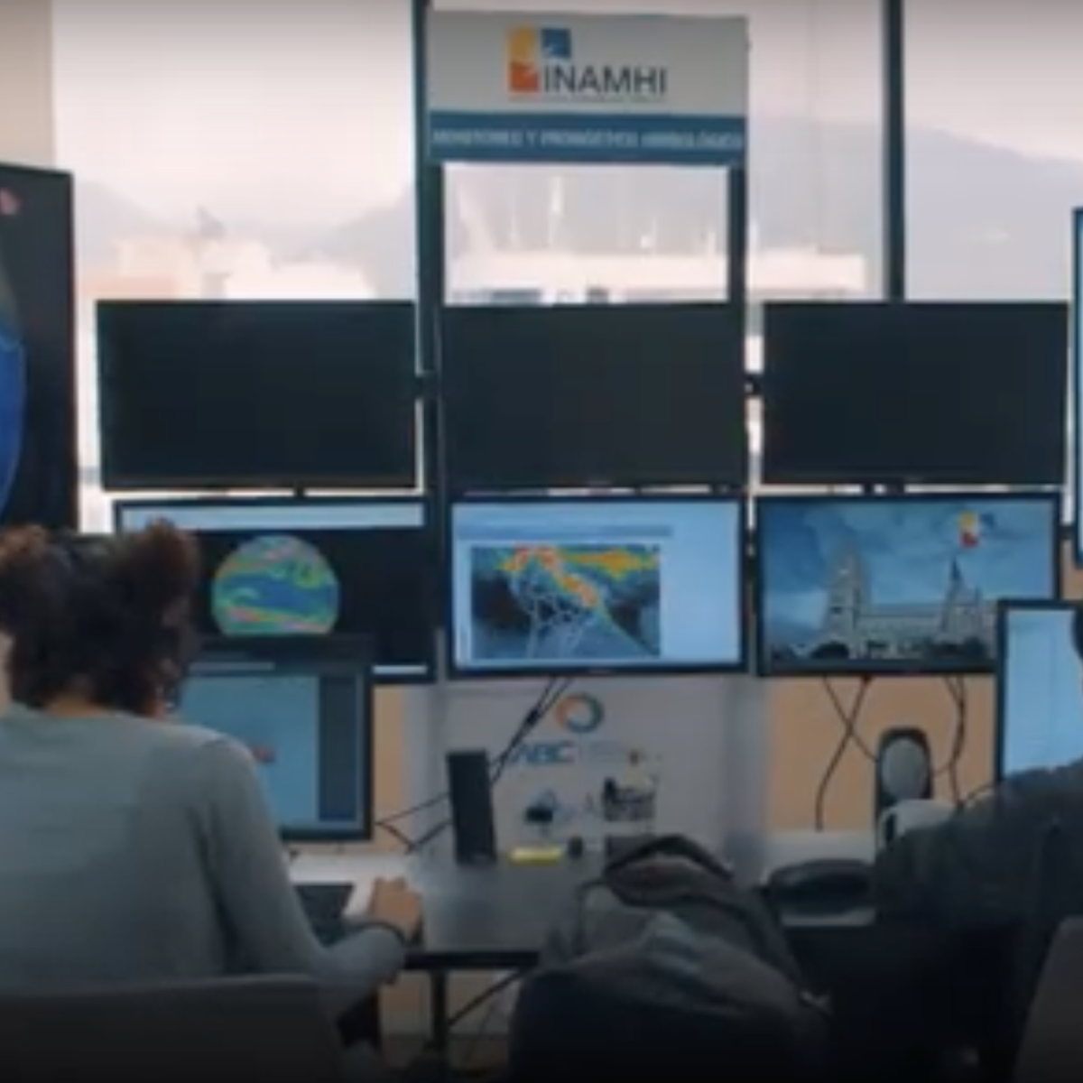 Two people in front of computers monitoring satellital images