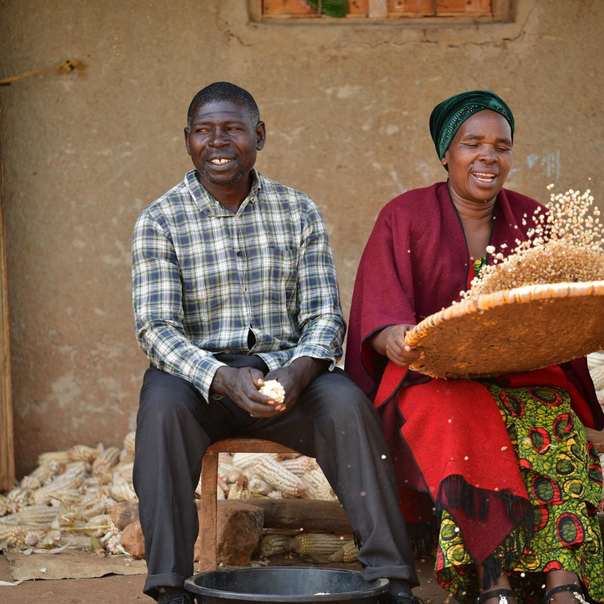 Anatoli and Paul sorting corn grain for their customers at their home in Rwamwanja refugee settlement. / AVSI Foundation