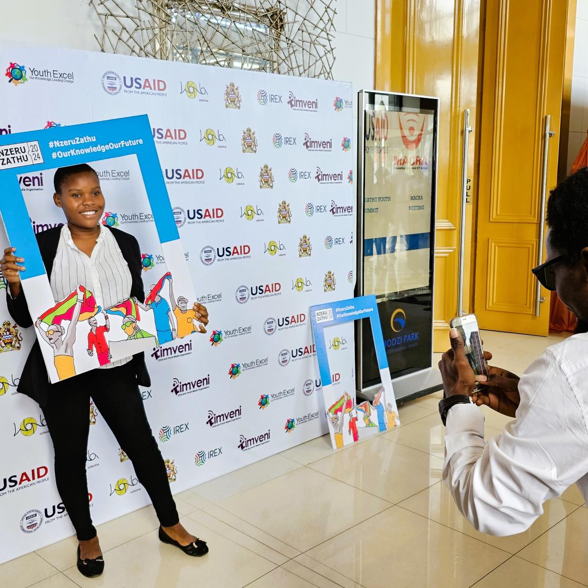 One of the participants in the Nzeru Zathu "Our Knowledge" Youth Summit poses for a photo in the open gallery outside the event hall. Photo: Oris Chimenya/USAID