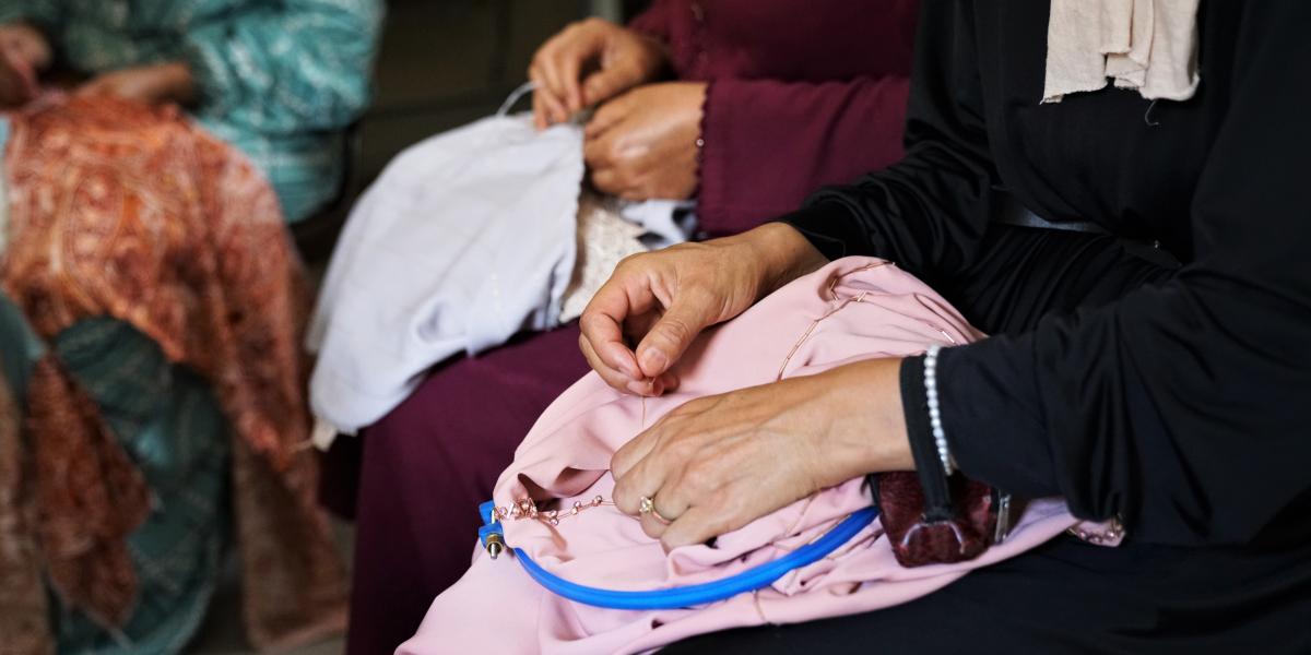 Hands of three women sew by hand