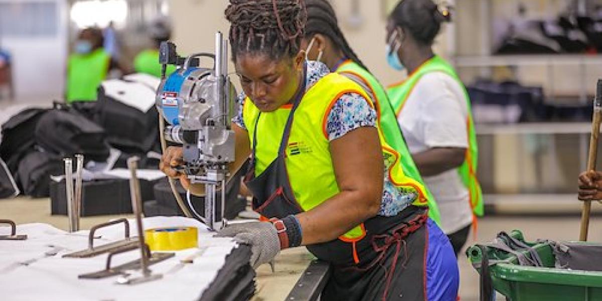 Woman wearing a yellow vest standing over a machine