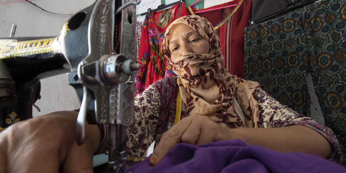 A woman sews on an antique sewing machine.