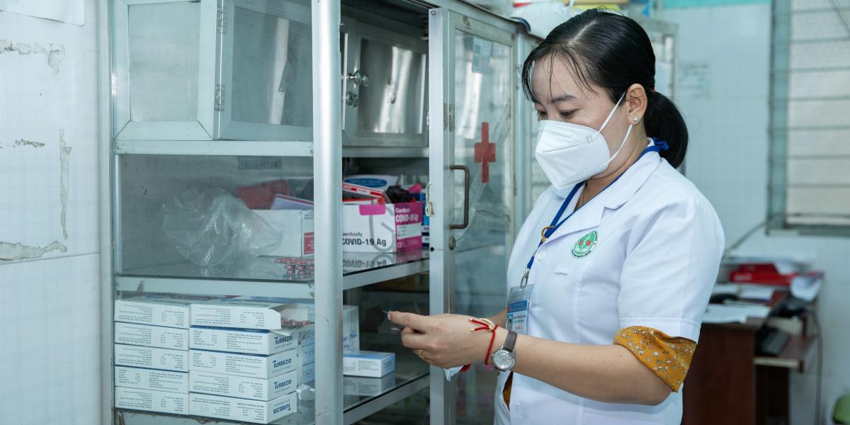 Nurse Le Thi Cam Giang showing Mr Vu on scanning the QRcode so that he could share with his family at An Tinh commune health centre. 