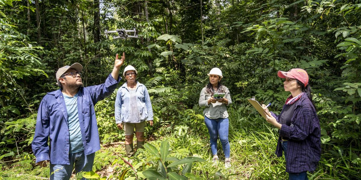 Four people flying a drone in the Amazon rainforest