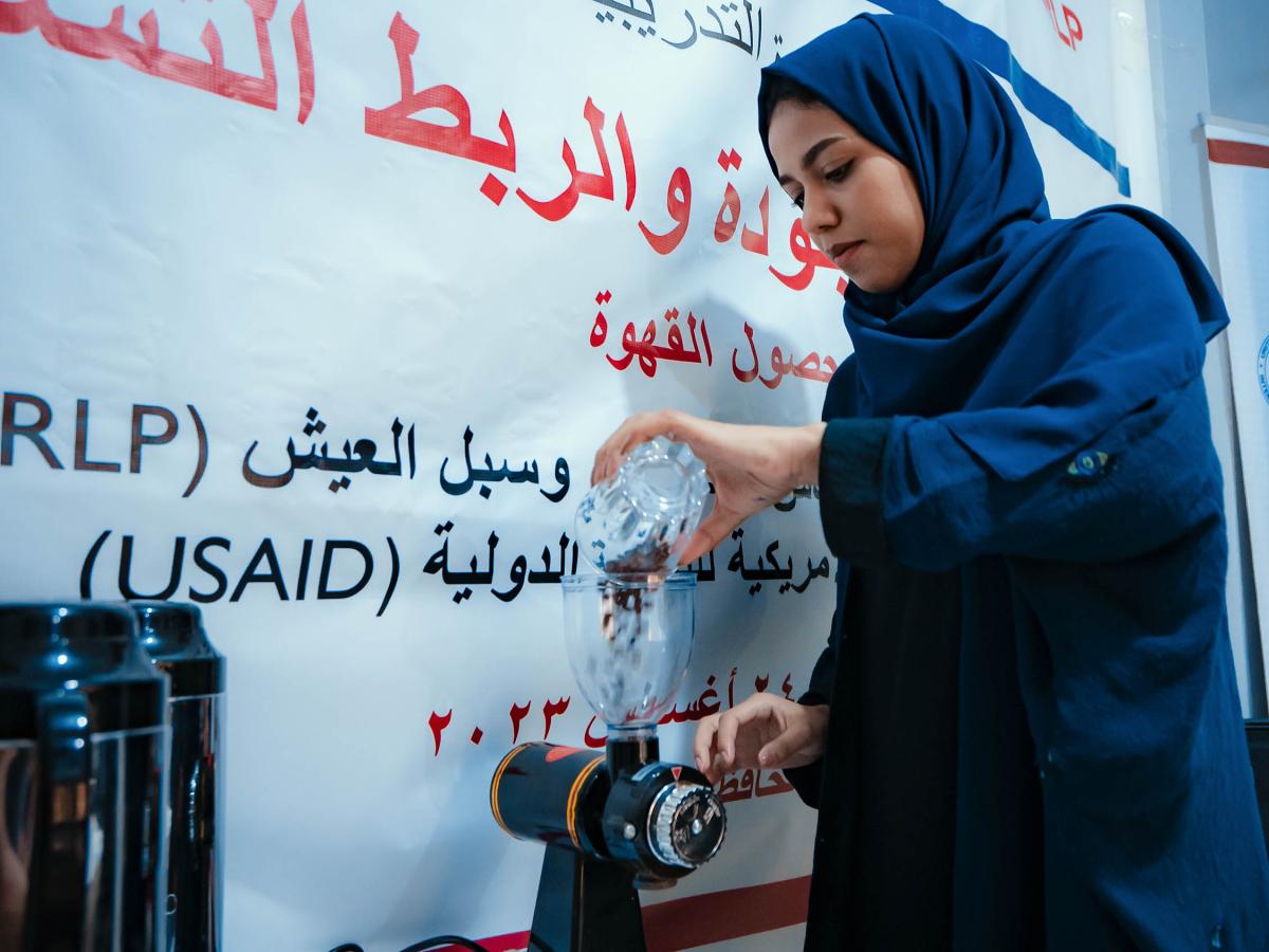 Coffee training participant pours coffee beans into grinder