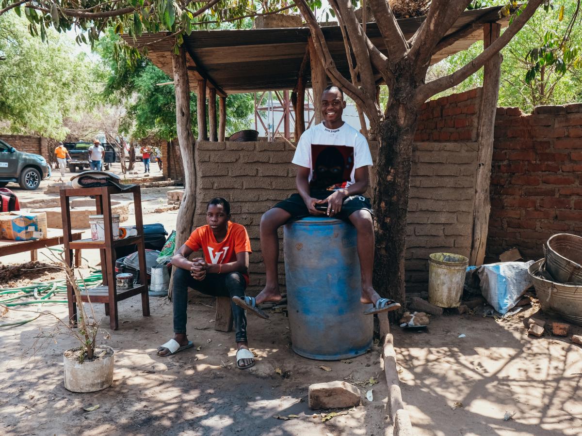 Residents sit with their belongings outside their house.