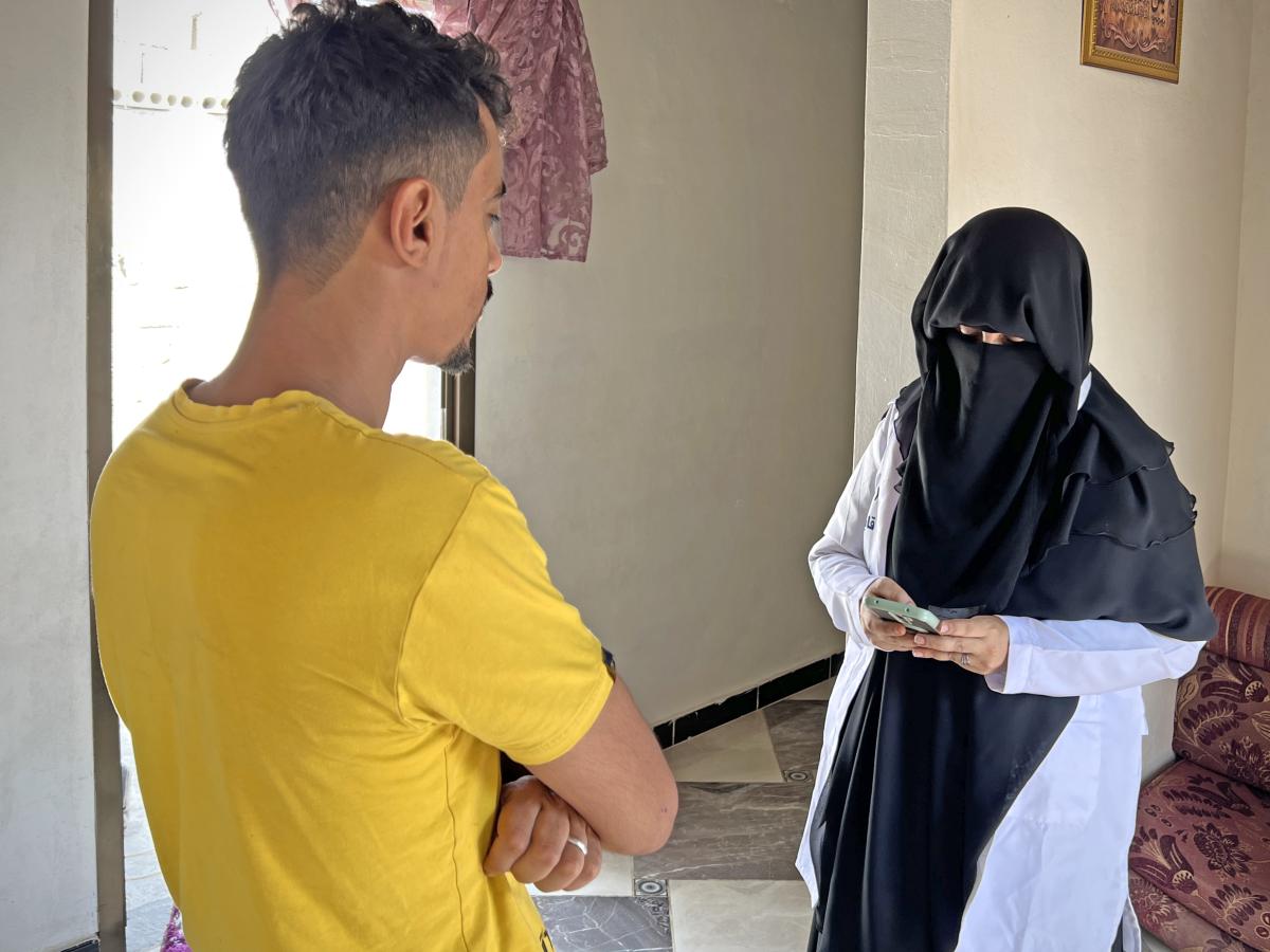 A USAID-trained community midwife collects the required information from a father to add him in the text vaccination reminder system in Al-Buraiqa district in Aden.