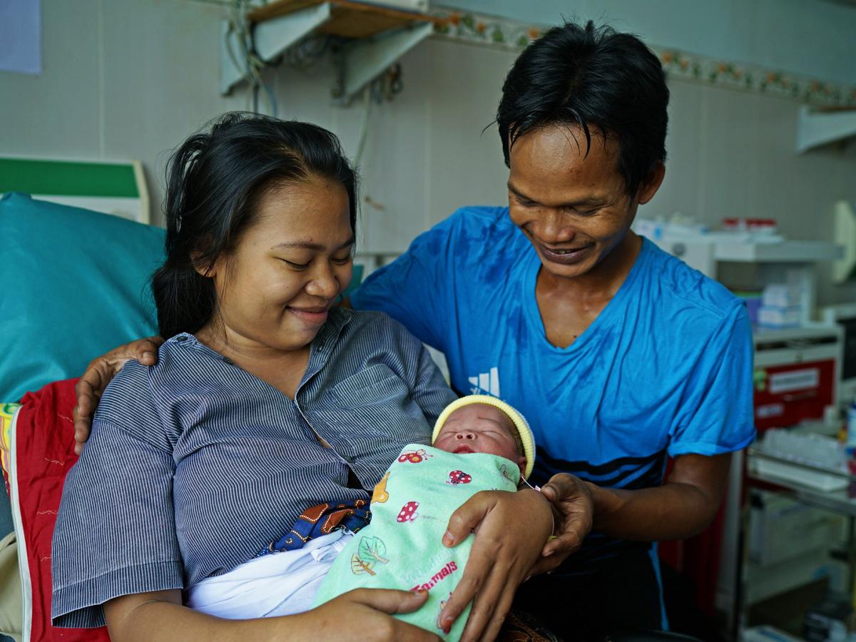 Bapak dan ibu menatap bayinya yang baru lahir dengan penuh cinta.