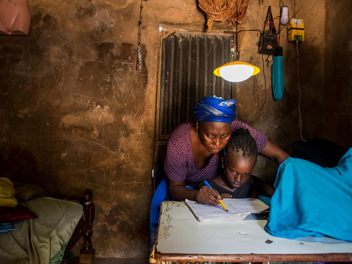 A mother teaching a child under a light in Senegal