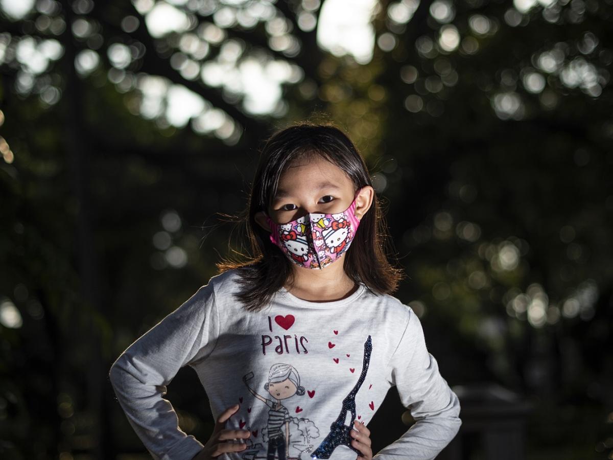 Seorang anak perempuan memakai masker. 