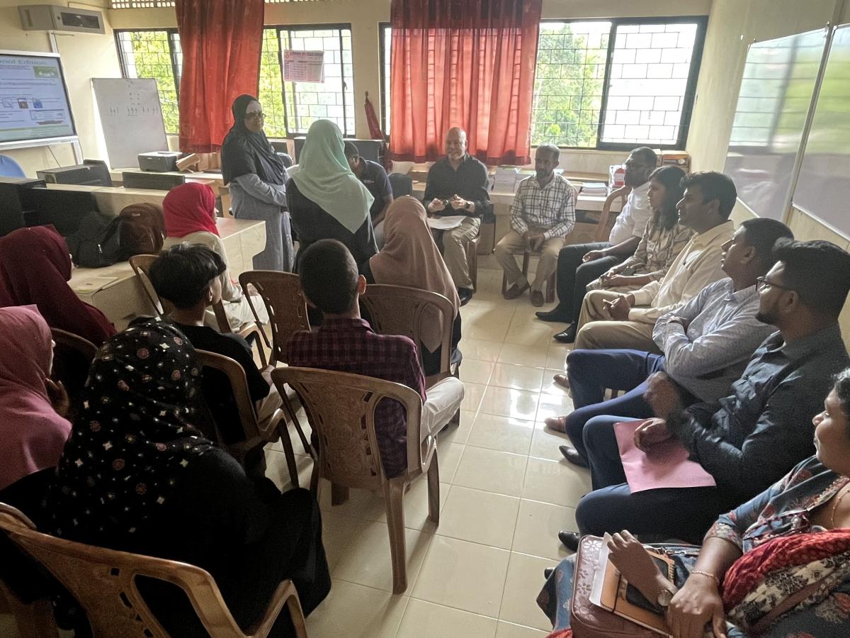 A classroom scene featuring a group of individuals seated in chairs, actively involved in a learning experience together.