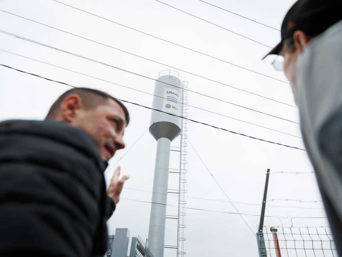 Two people watching a new water tower with USAID logo