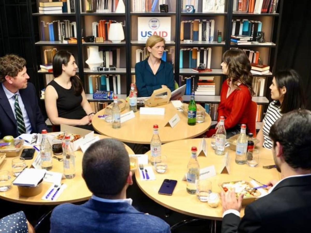 a group of people sit around small tables 