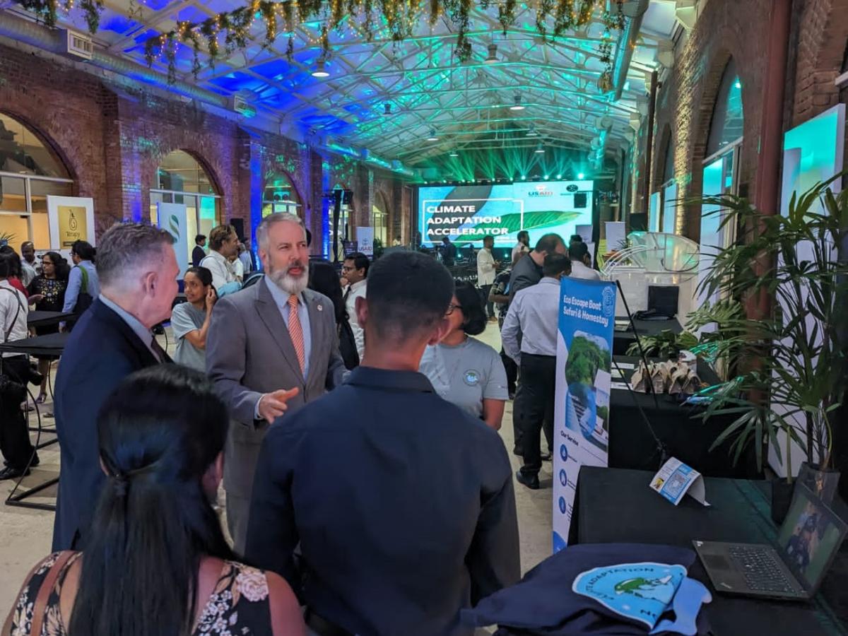 A group of people talk around a display table at and exhibition.