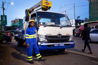 A woman leans on a service truck while inspecting street lights