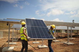 Two men lift up a solar panel