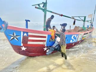 Hackman offloading a gallon of water to a fishing crew about to embark on an expedition.