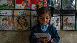 Young Nepali girl reads a book at school. USAID is partnering with Nepal to improve educational access and quality.