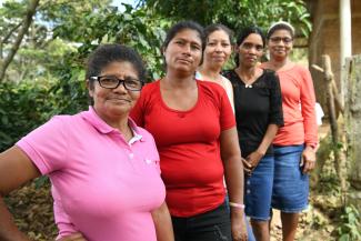 Group of indigenous Honduran women pose a group and smile at the camera.