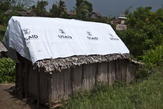 Bâche de l'USAID sur le toit d'une hutte en bois dans la campagne malgache.