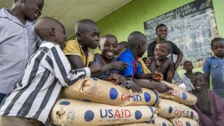 Group of smiling boys leaning on USAID food bags