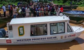 USAID/Ghana Mission Director, Kimberly Rosen, Ghana Health Service representatives, and traditional leaders cut the ribbon to officially hand over boats to the community.