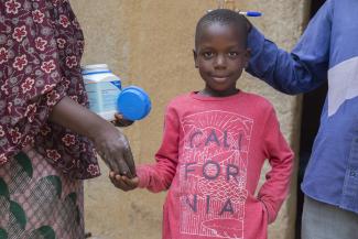 A boy in Mali is handed a dose of medicine to help prevent a neglected tropical disease 